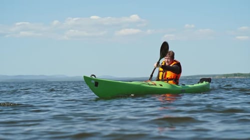 Man Paddles Kayak on Lake in Summer