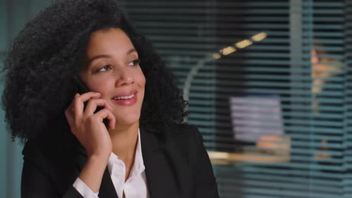 Cheerful Woman Laughing and Talking on Phone at Work