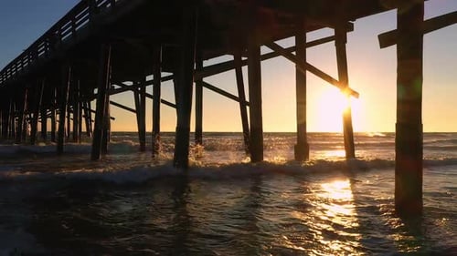 Waves rolling in at sunset under the pier at Newport Beach