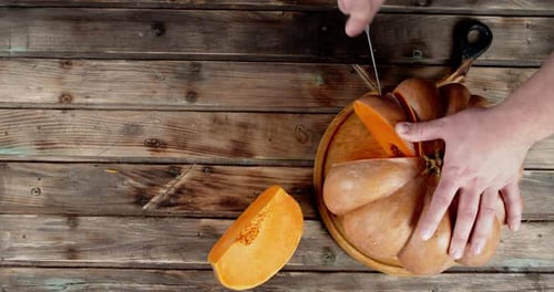 Male Hand with Knife and Cut Pieces From the Big Pumpkin.