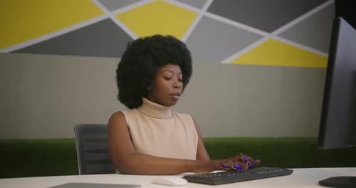 African American Woman Types on Keyboard in Office Room