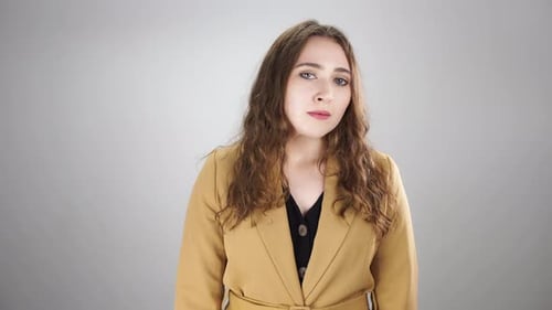 Mujer furiosa está de pie sobre fondo blanco y cruzando los brazos luciendo nerviosa