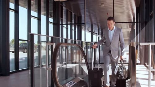 Elegant businessman walking with suitcase along the airport. Young mail entrepreneur.