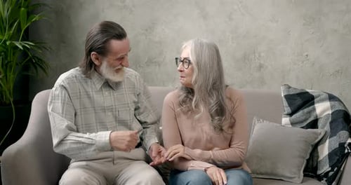 Senior Couple Talking on Couch Holding Hands