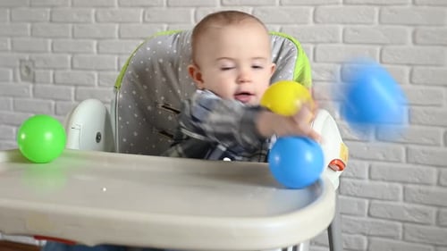 Baby Playing with Balls in High Chair