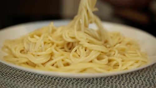 White plate with spaghetti on the kitchen table, close-up