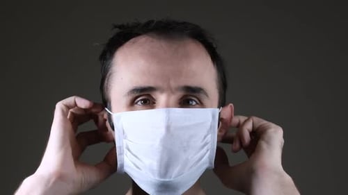 Man Putting on a White Disposable Face Mask