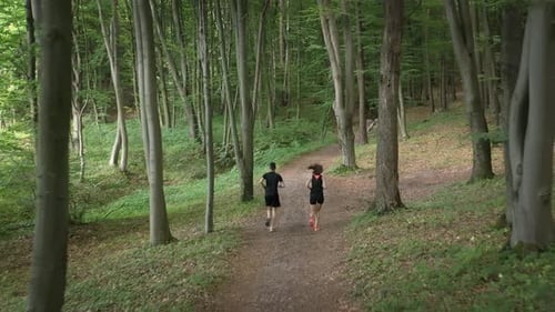 Couple Runs Through Green Forest Path