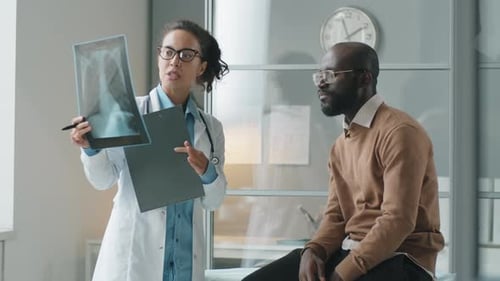 Female Doctor Explaining Chest X-Ray to African American Man in Clinic