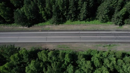 Drohne Point of View Aufnahme eines weißen Lastwagens, der auf der Highway Road im Wald fährt