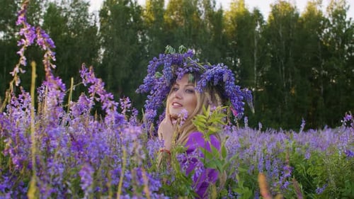 Beautiful Young Woman in Flower Wreath on Meadow at Springtime