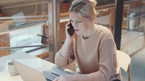 Woman Talking on Phone While Using Laptop