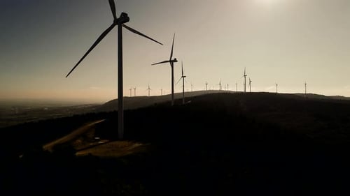 Wind Turbines Silhouetted on Hilltop at Sunrise