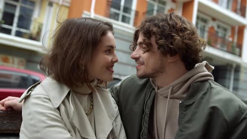 Couple Sitting on Bench Leaning in for Kiss