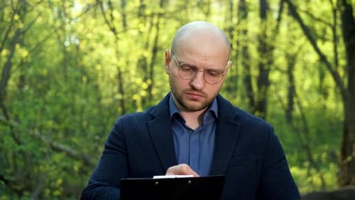 Adult Man Taking Notes Outside in Nature