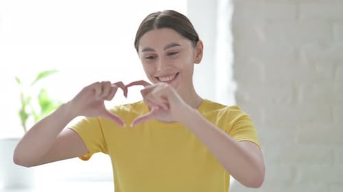 Young Woman Making Heart Shape with Hands