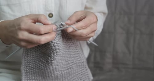 Knitting a gray wool textile by hand