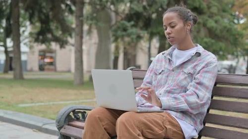 Woman On Bench Types on Laptop in Park