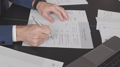 Man Reviews Resume on Black Desk Close Up