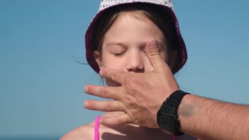Father Apply Protective Sunscreen on Daughter Nose at Beach on Summer Vacation