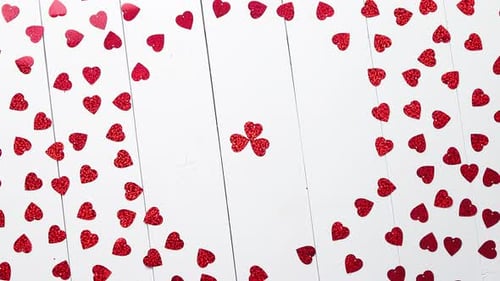 Vlentine's Day Composition. Heart Shaped Sequins Placed on White Wooden Table