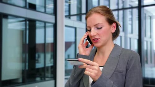 Professional Woman on Phone with Credit Card in Office