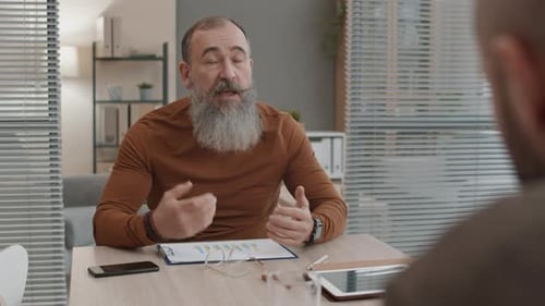 Bearded Man Discusses Charts at Office Meeting