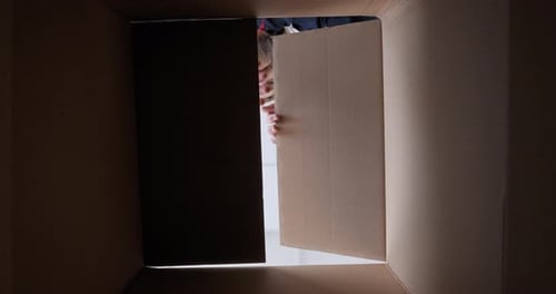 Überraschter kaukasischer bärtiger Mann schaut in ausgepackte gelieferte Cartoon-Box mit Bestellung Überraschte Gefühle