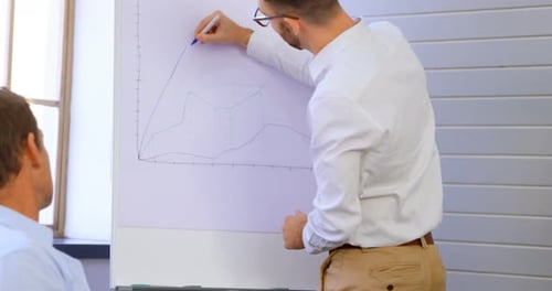 Men Collaborating and Drawing Graphs on Whiteboard