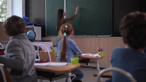 Female Teacher Writing Math Equatian on Blackboard