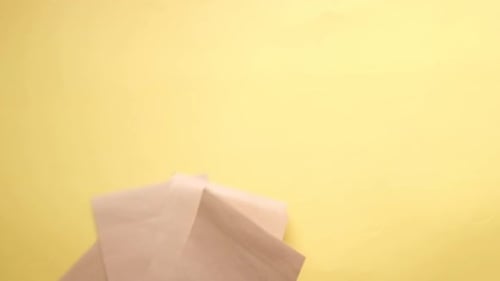 Slow Motion of Empty Paper Dropping on Yellow Background