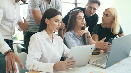 Group Brainstorming on Tablet and Laptop in Office