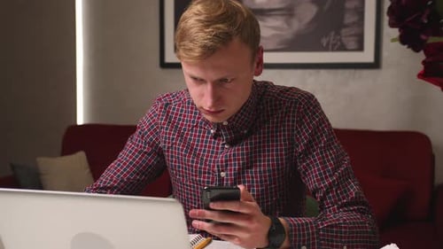 Handsome Caucasian Man Using Laptop Typing on Phone Working at Home Office Desk