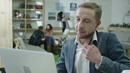Man on Phone Working on Laptop in Office