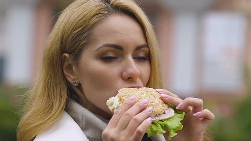 Woman Enjoys Burger During Lunch Outside