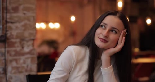 Coquettish Woman Leaning Head on Hand in Cafe