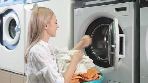 Woman Loading Clothes Into Modern Washing Machine