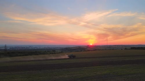 Tractor Spraying Fertilizers with Insecticide Herbicide Chemicals on Agricultural Field at Sunset