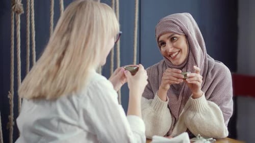 Zwei Mädchen unterhalten sich drinnen beim Tee nett.