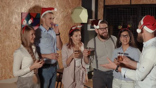 Un homme barbu dit un toast à des amis lors d'une fête de Noël en train de trinquer et de boire