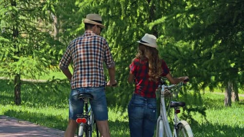 Couple Strolling with Bicycles in Sunny Park