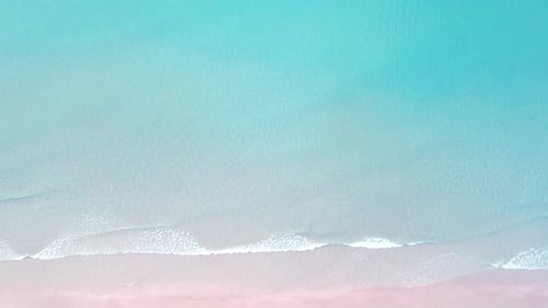 4K-Luftaufnahme von oben auf die Drohne, die blauen Meereswellen und den wunderschönen rosa Sandstrand.
