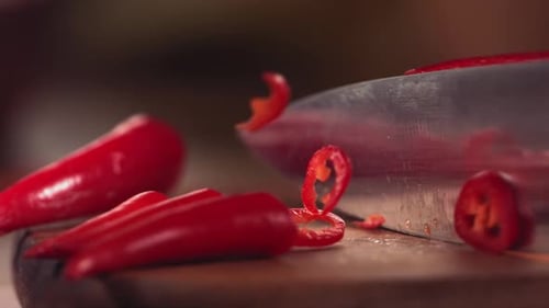 Knife Cutting Red Chilli Pepper on Wood in Slow Motion