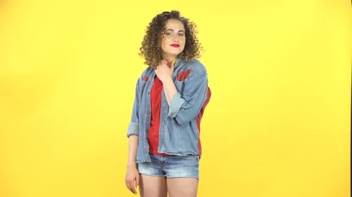 Chica rizada sonríe coquetamente mientras mira a la cámara, construye sus ojos, de manera seductora
