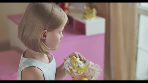 Seitenansicht Nahaufnahme des Gesichts eines kaukasischen Mädchens, das in die Kamera schaut und beim Spielen mit ihrer Puppe signiert