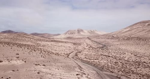 Path road in the middle of a mountains sand desert with blue bright sky in background. Arid climate