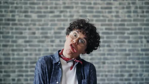 Retrato de jovem alegre fazendo caretas engraçadas no fundo do tijolo