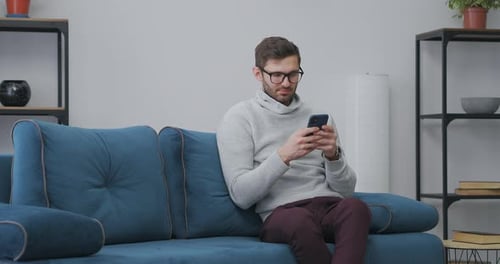 Introvert is Spending Weekend at Home Using Smartphone Surfing Internet Sitting Alone on Couch in