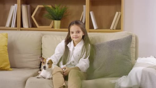 Happy Girl Sitting with Pet Dog on Couch