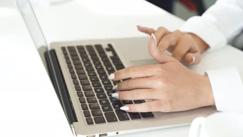 Hands Typing on a Laptop in a Bright Office